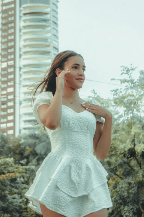 a woman in a short white dress standing in front of a tall building