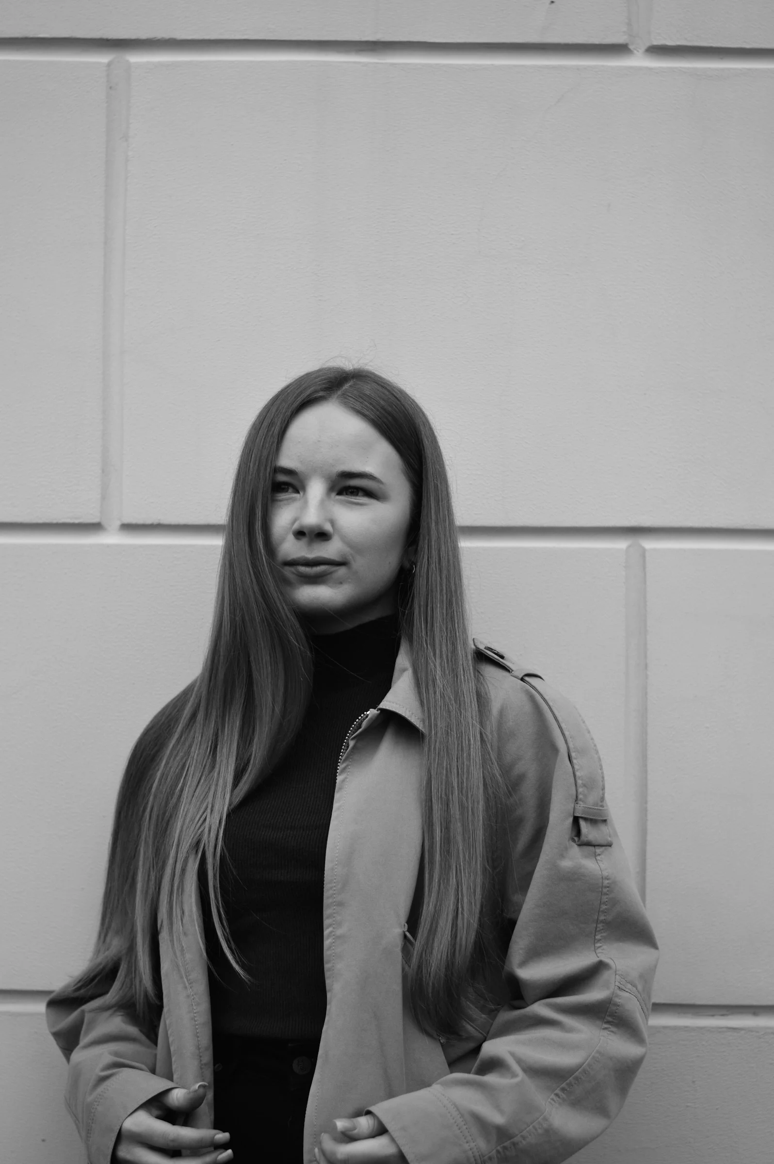 Young woman in trench coat against textured wall