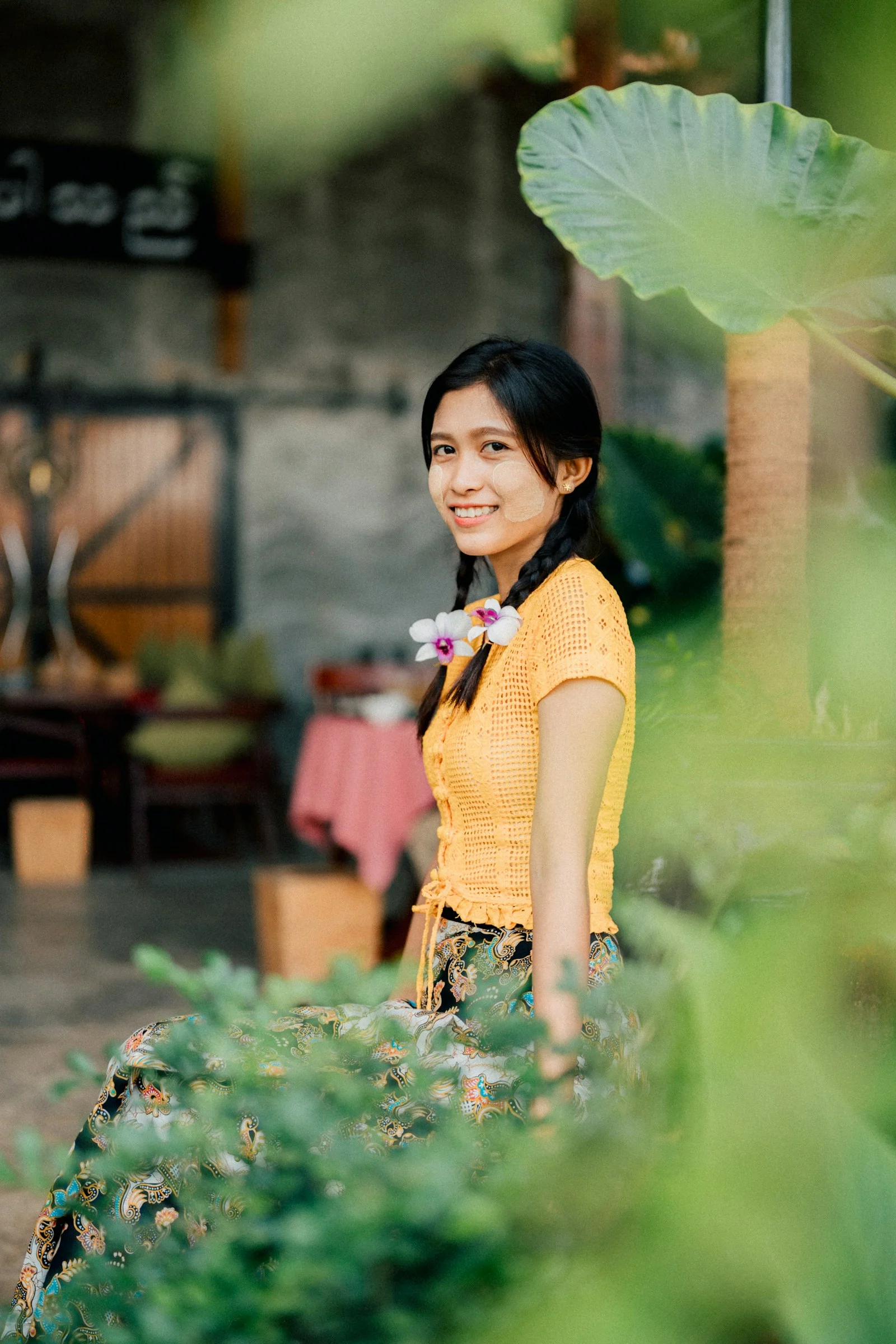 A young woman smiles, adorned with a flower