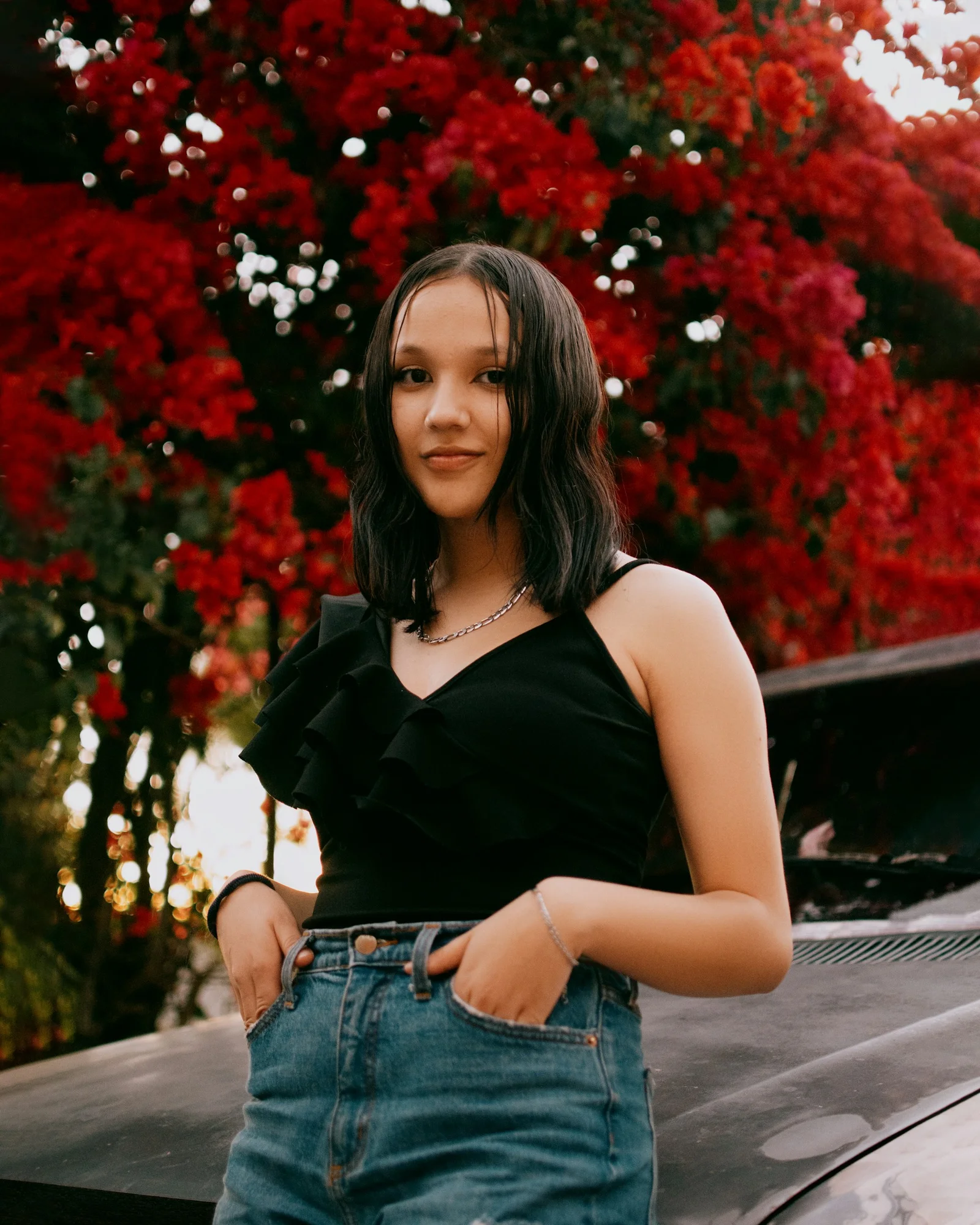 a woman standing next to a car in front of a tree