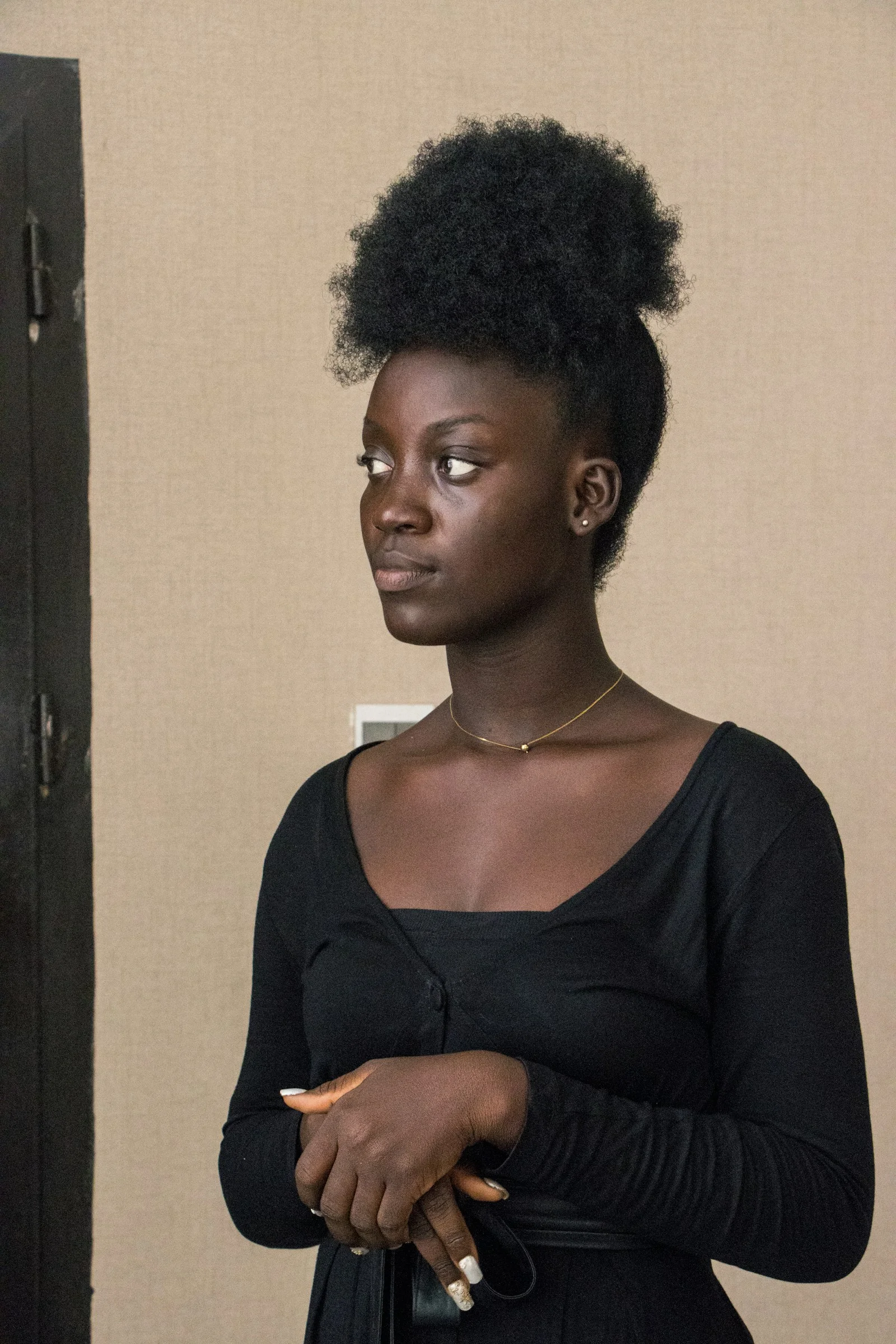 A young woman in a black dress looking left