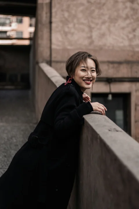 白天穿黑色外套的女人倚靠在混凝土墙上