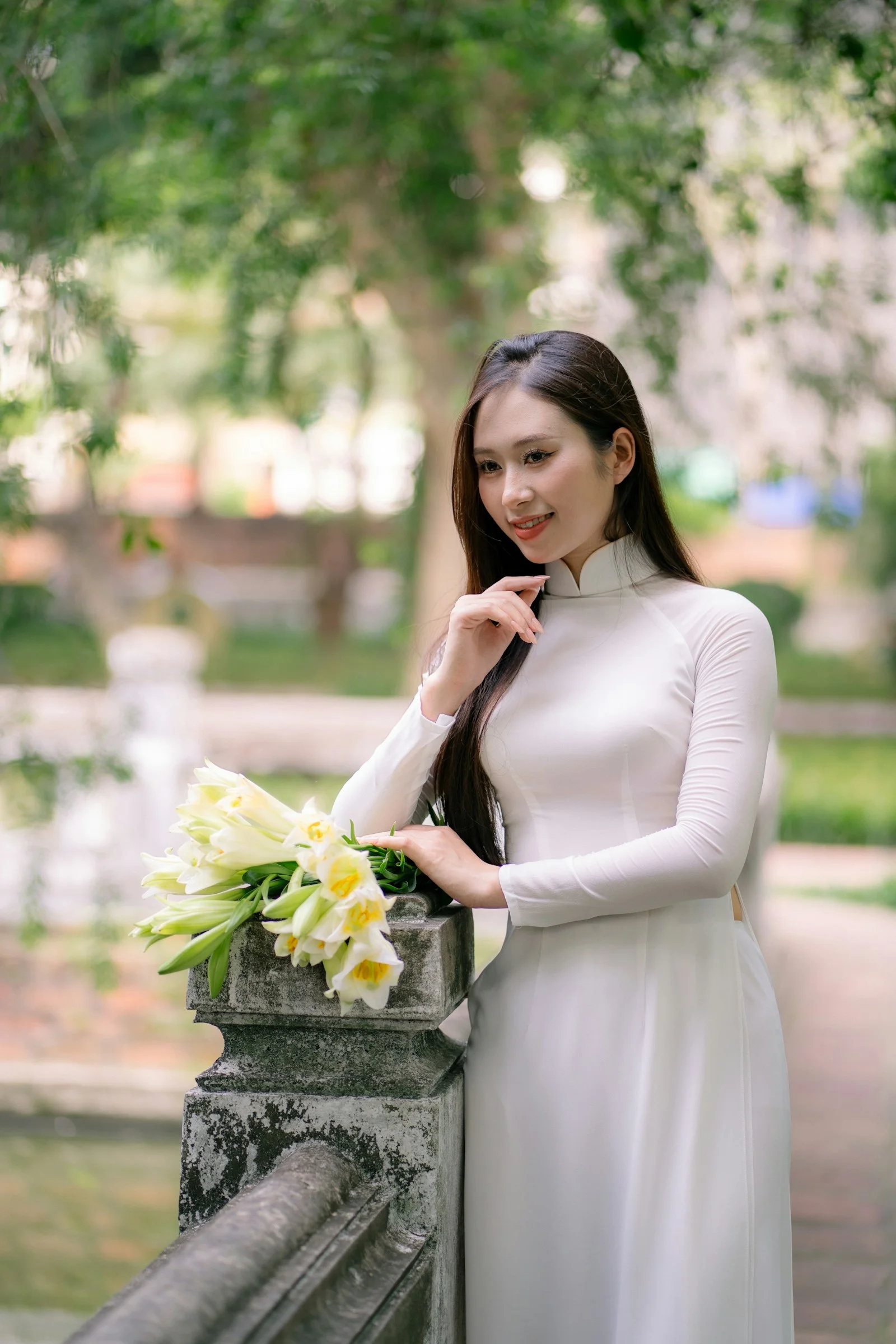 身穿白色连衣裙的年轻女子手持鲜花摆姿势