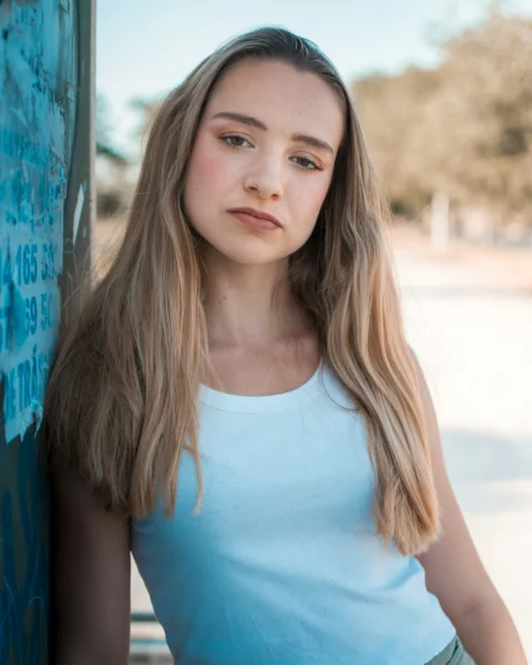 Young woman with long blonde hair leaning against wall