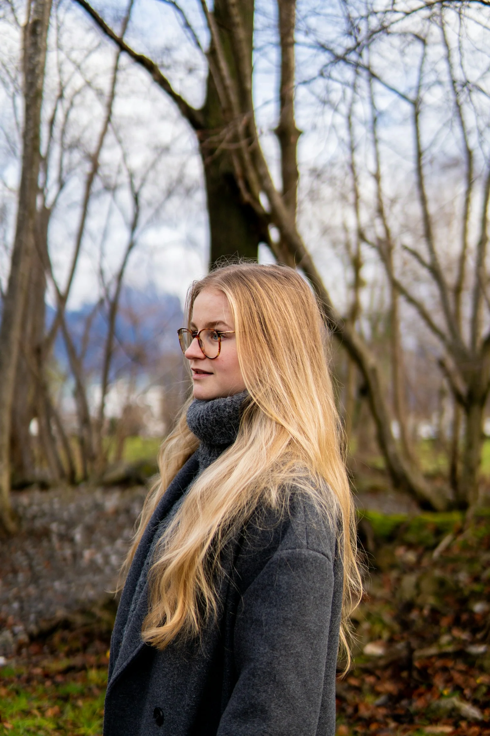 a woman with long blonde hair standing in the woods