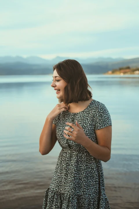 a woman standing on a beach next to a body of water