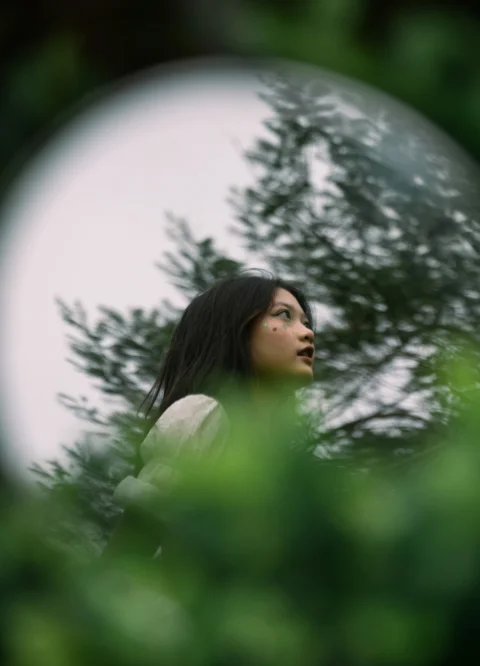 站在樹前抬頭望天的女子