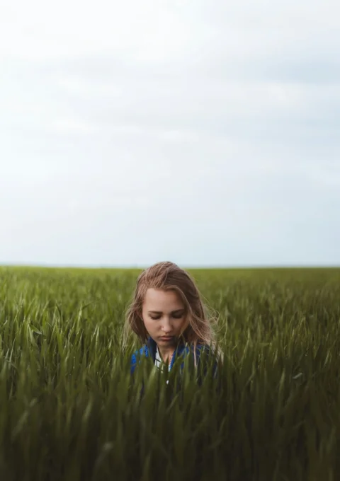 girl in blue and white shirt standing on green grass field during daytime