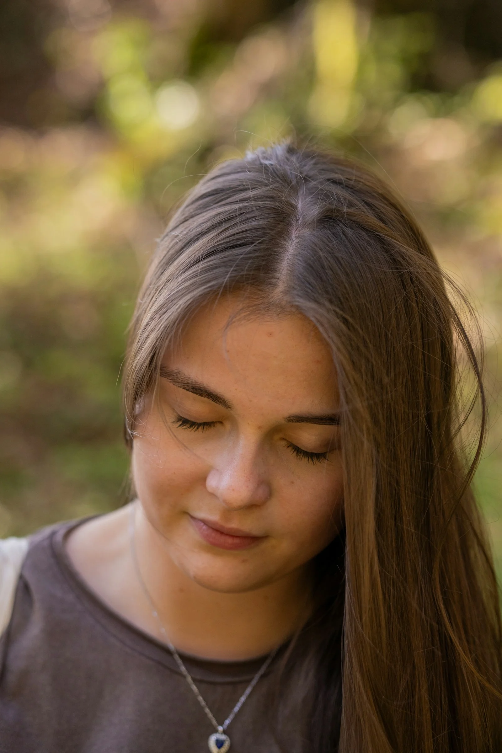 A woman with long hair looking down at her cell phone