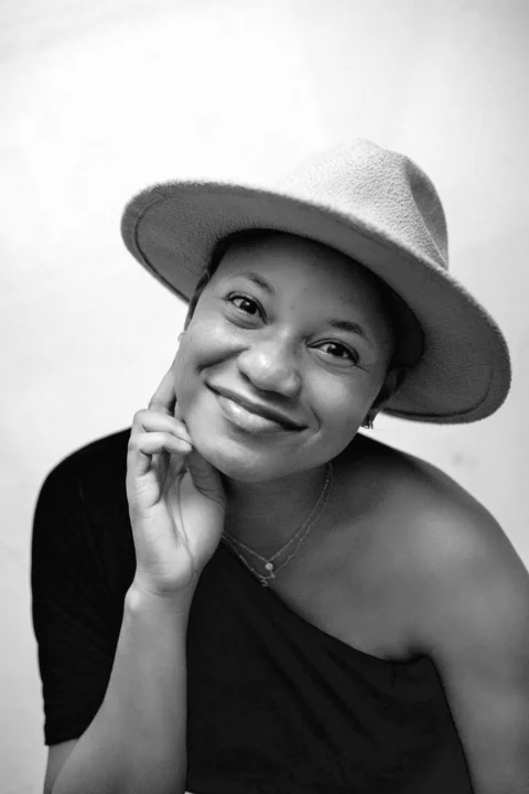 A black and white photo of a woman wearing a hat