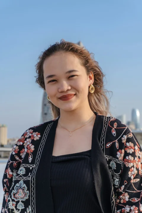 年輕女子在戶外微笑，背景是城市天際線