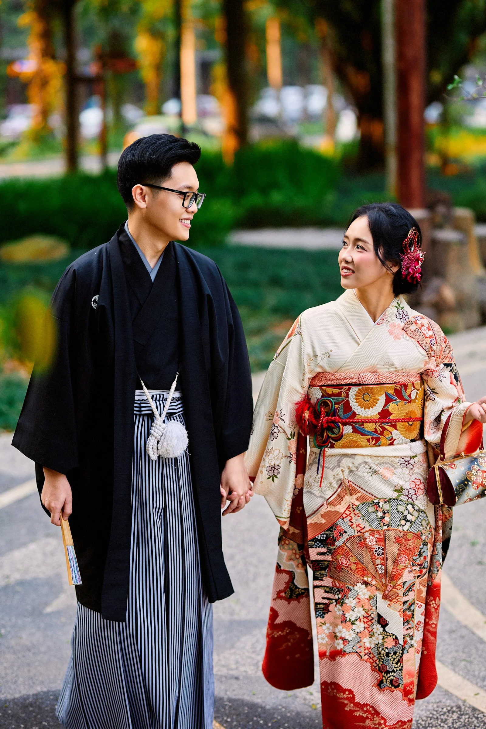 Japanese couple in kimonos holding hands and smiling outdoors