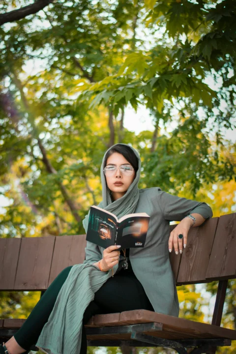 woman in black hoodie sitting on brown wooden bench