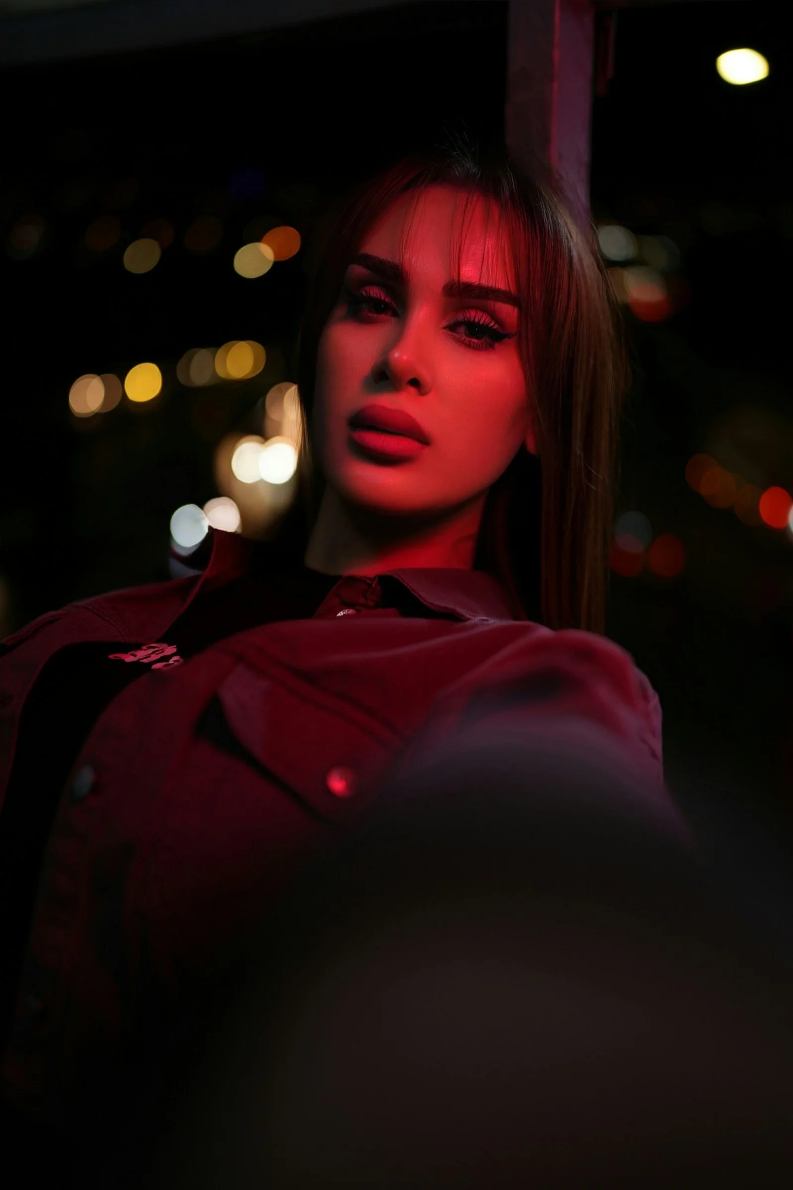 Woman illuminated by red light at night with bokeh lights