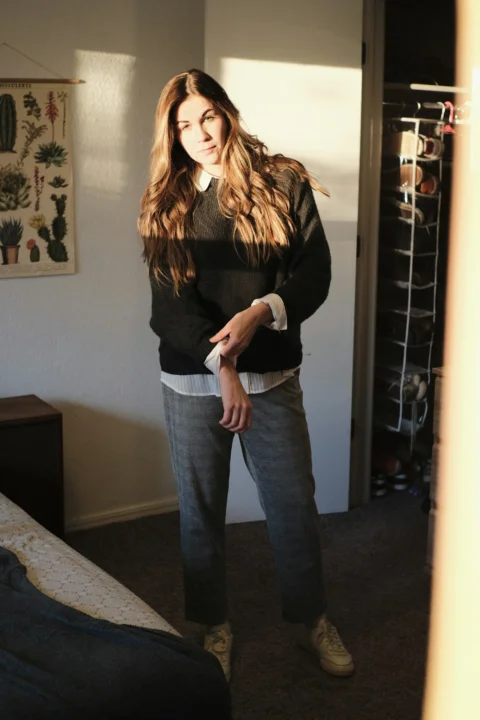 a woman standing in a room with her hands in her pockets