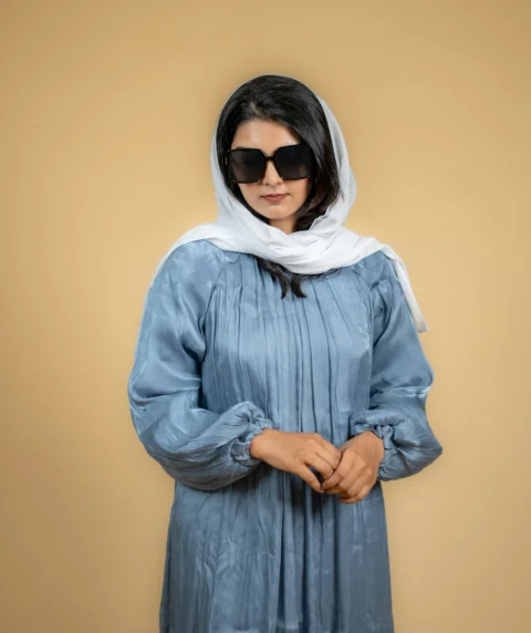 a woman wearing a blue dress and a white scarf