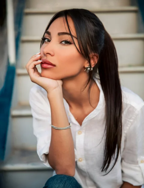 A woman with a high ponytail in a white shirt on outdoor stairs
