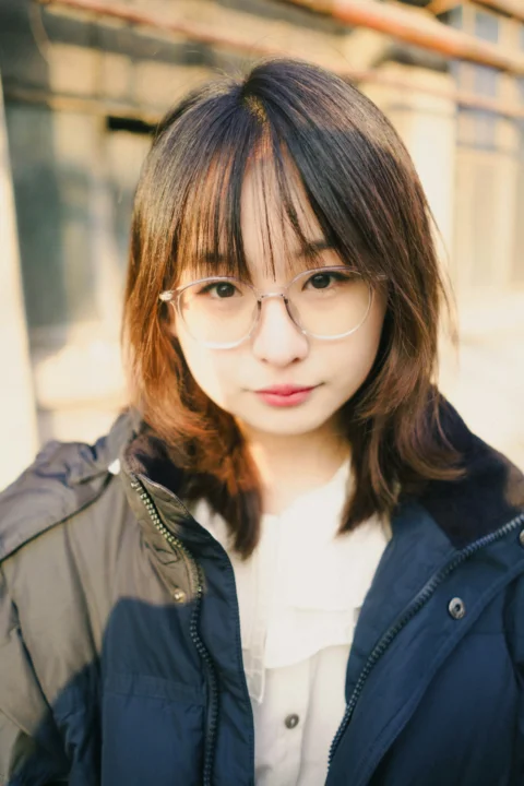 A woman with glasses standing in front of a building