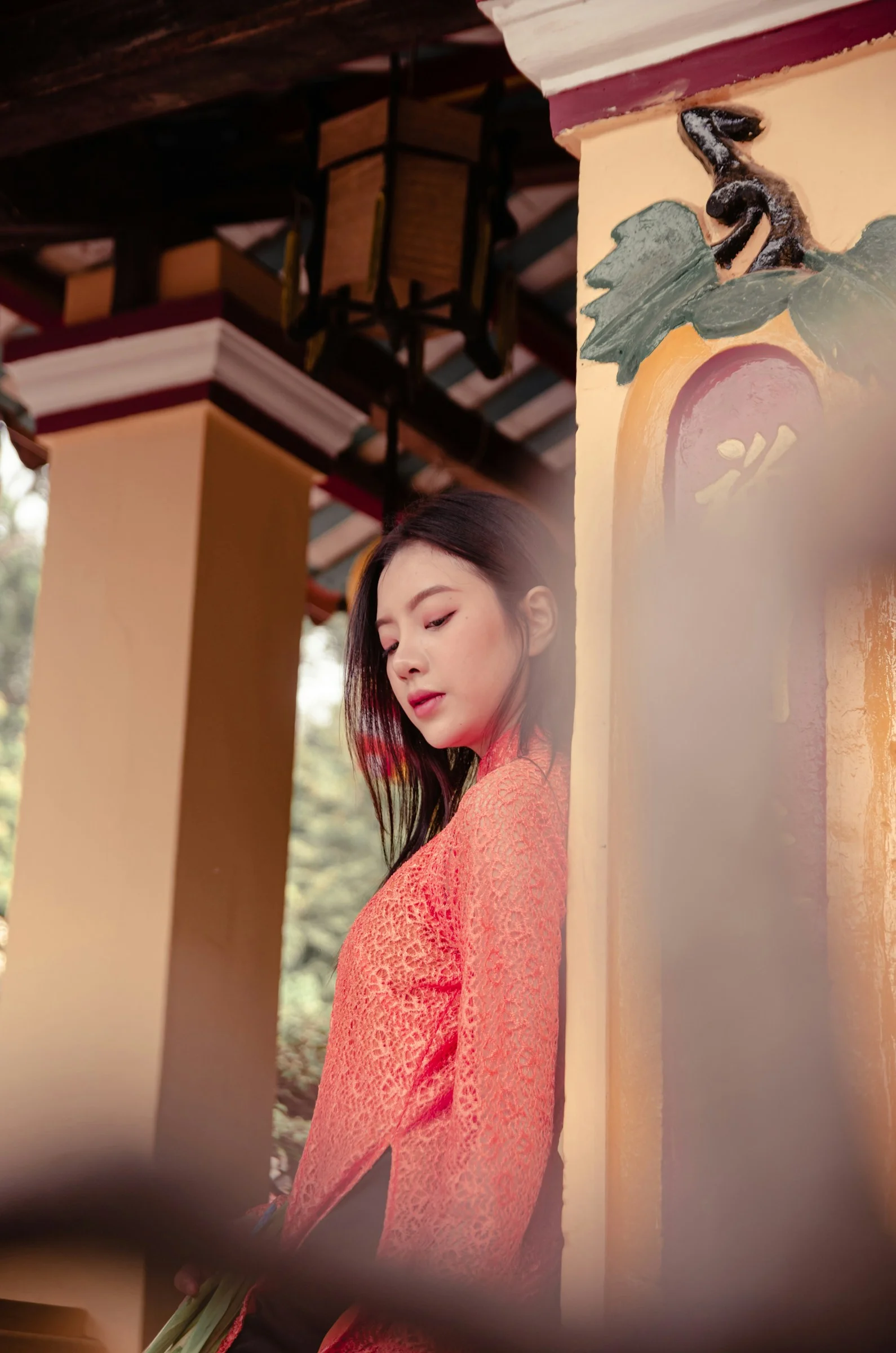 一位穿紅色連身裙靠在牆上的女子