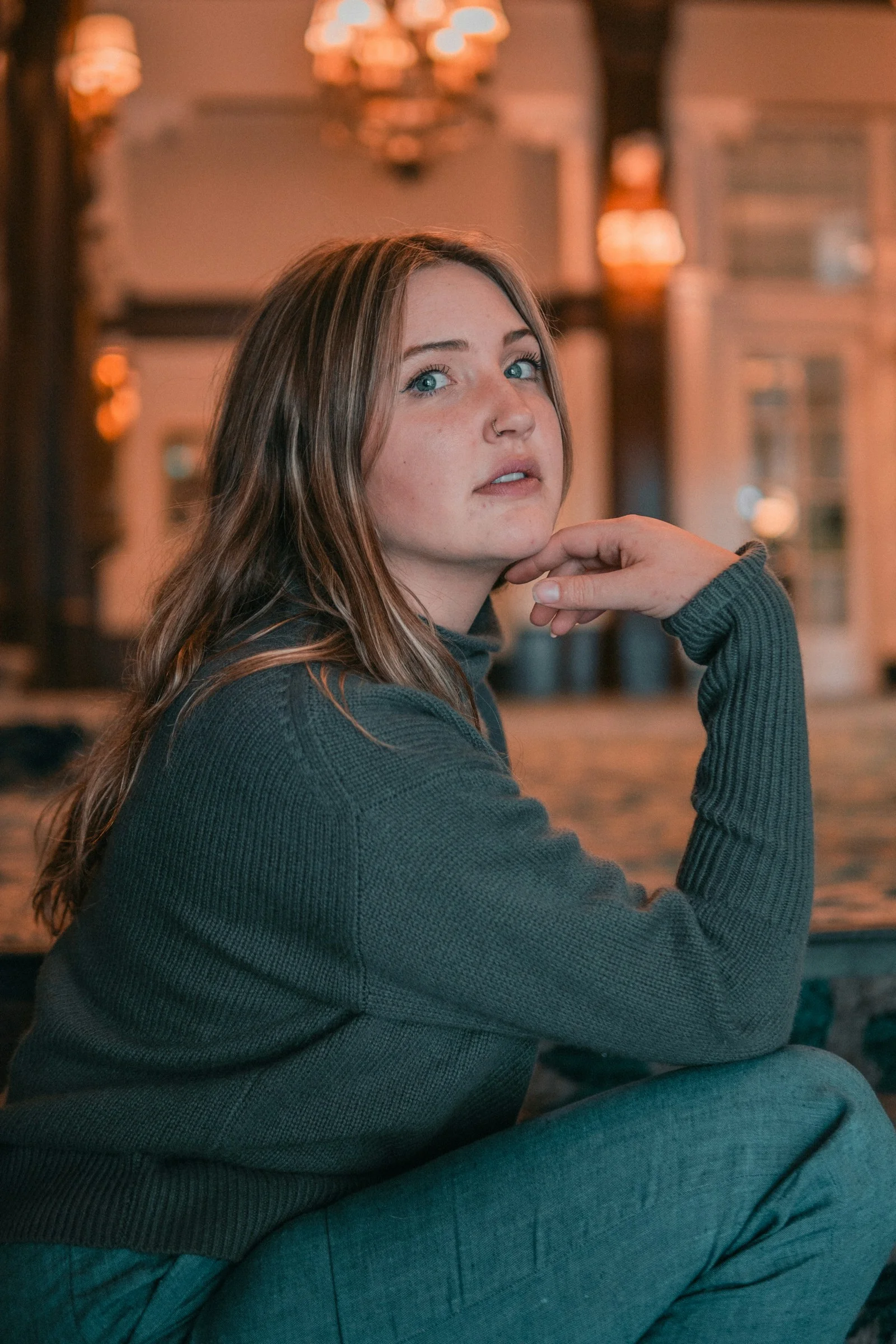 A woman in a dark green sweater resting her chin on her hand
