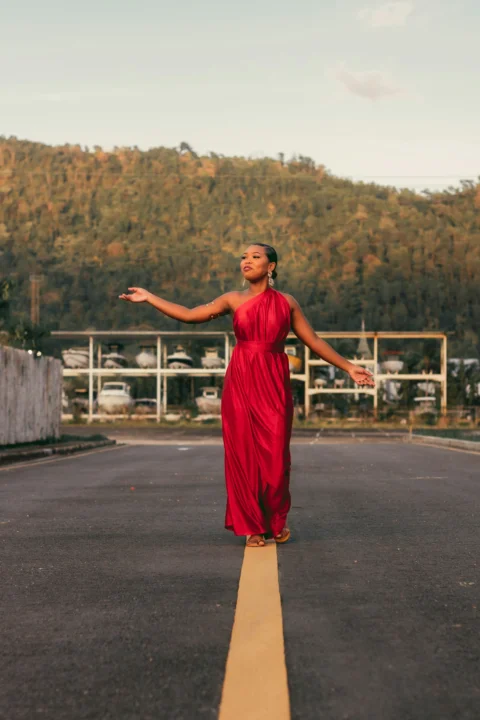 a woman in a red dress standing on a road