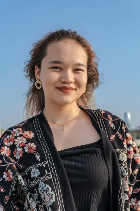 Young woman with floral jacket smiles outdoors