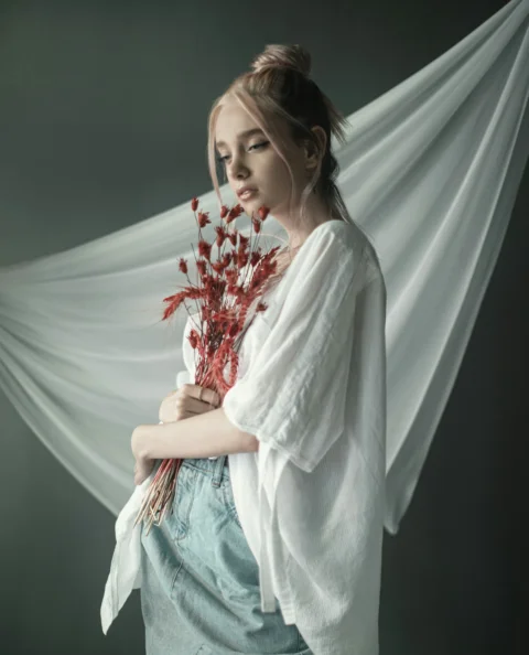 woman in white long sleeve shirt holding red flowers