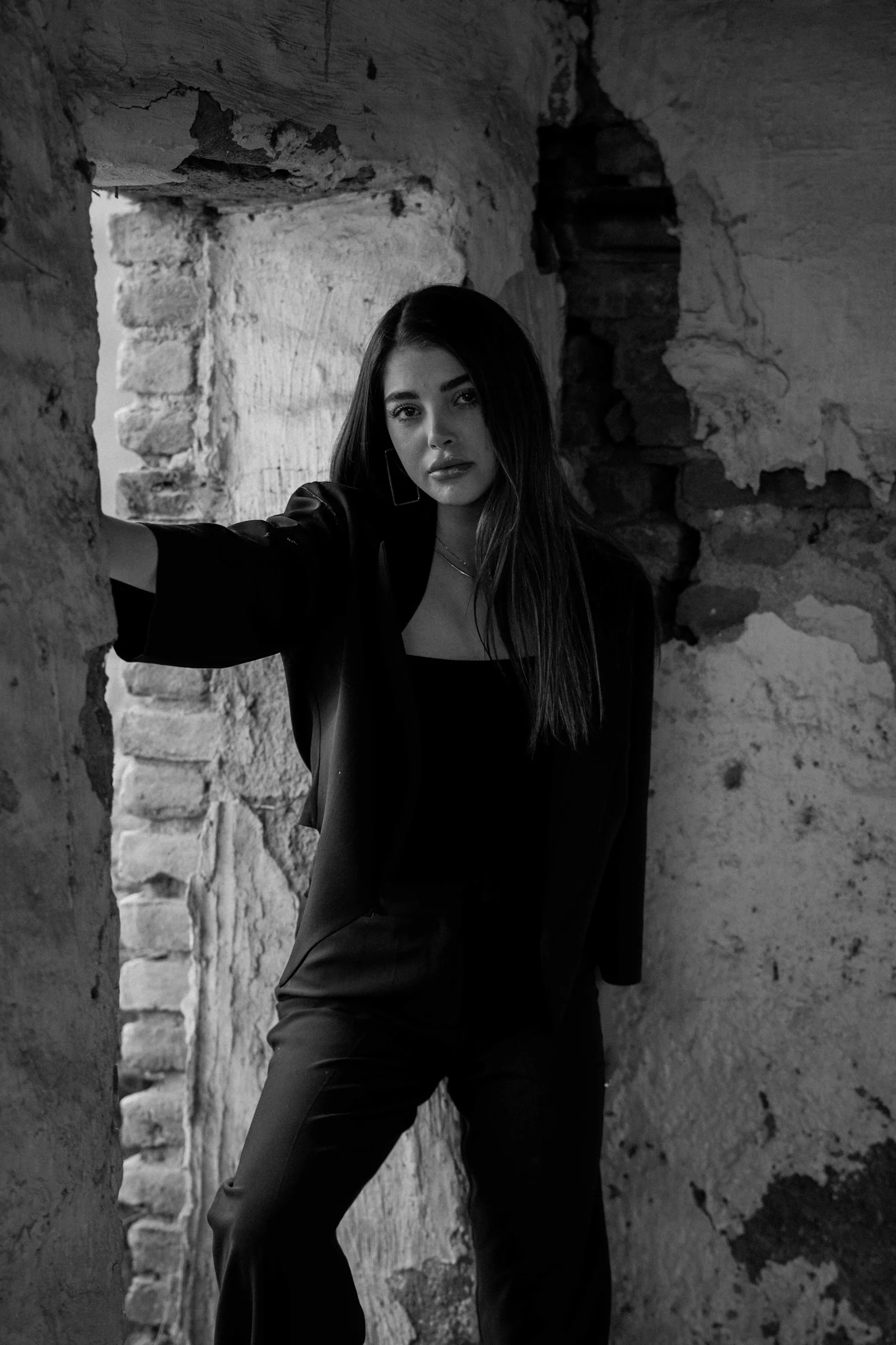 A woman in black clothing stands in a ruined building