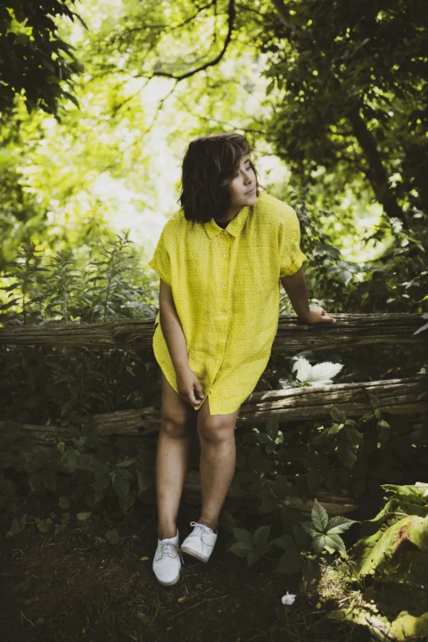 woman in yellow dress standing on brown wooden bridge