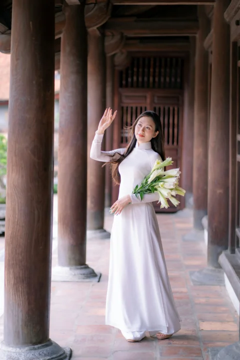 女子手持鲜花挥着手，走在寺庙中