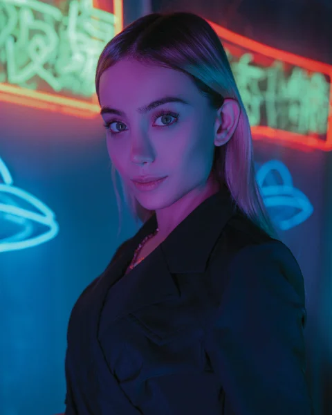 a woman standing in front of a neon sign