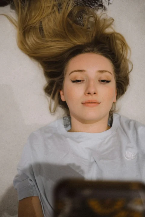 a woman laying on the floor with her hair blowing in the wind