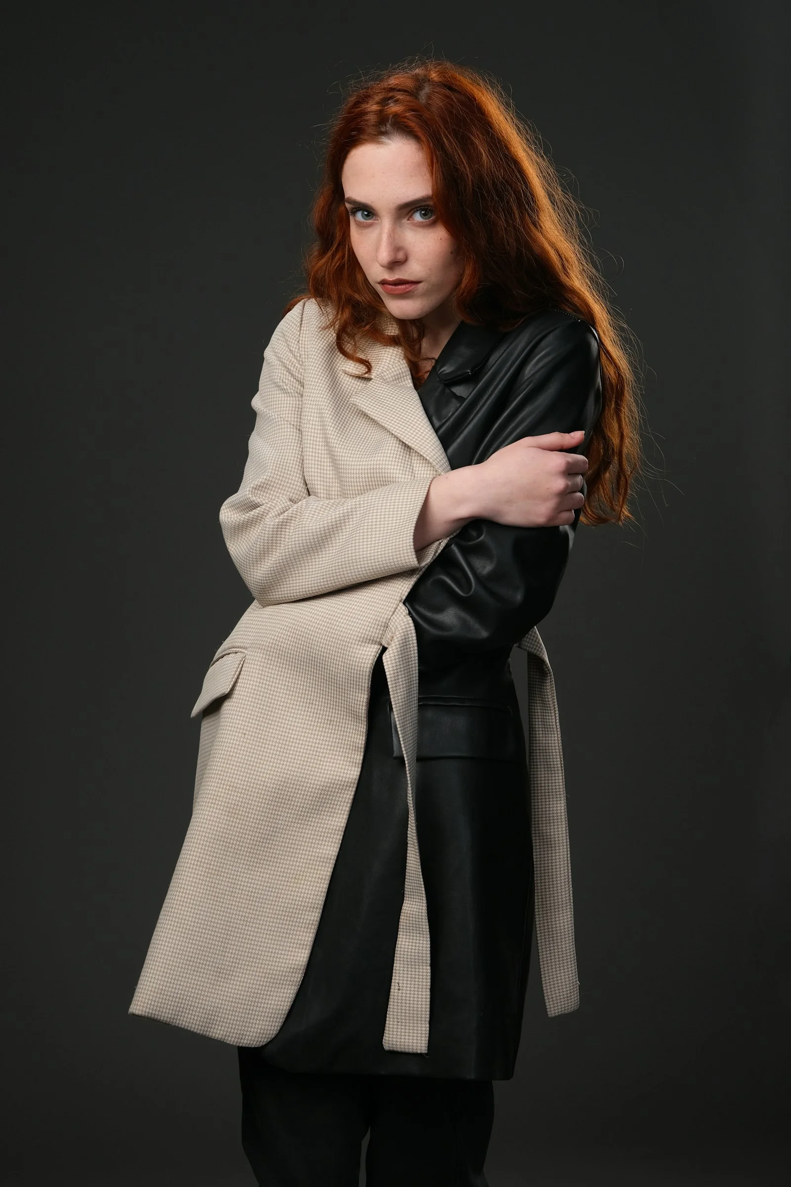 a woman with red hair wearing a coat and black pants