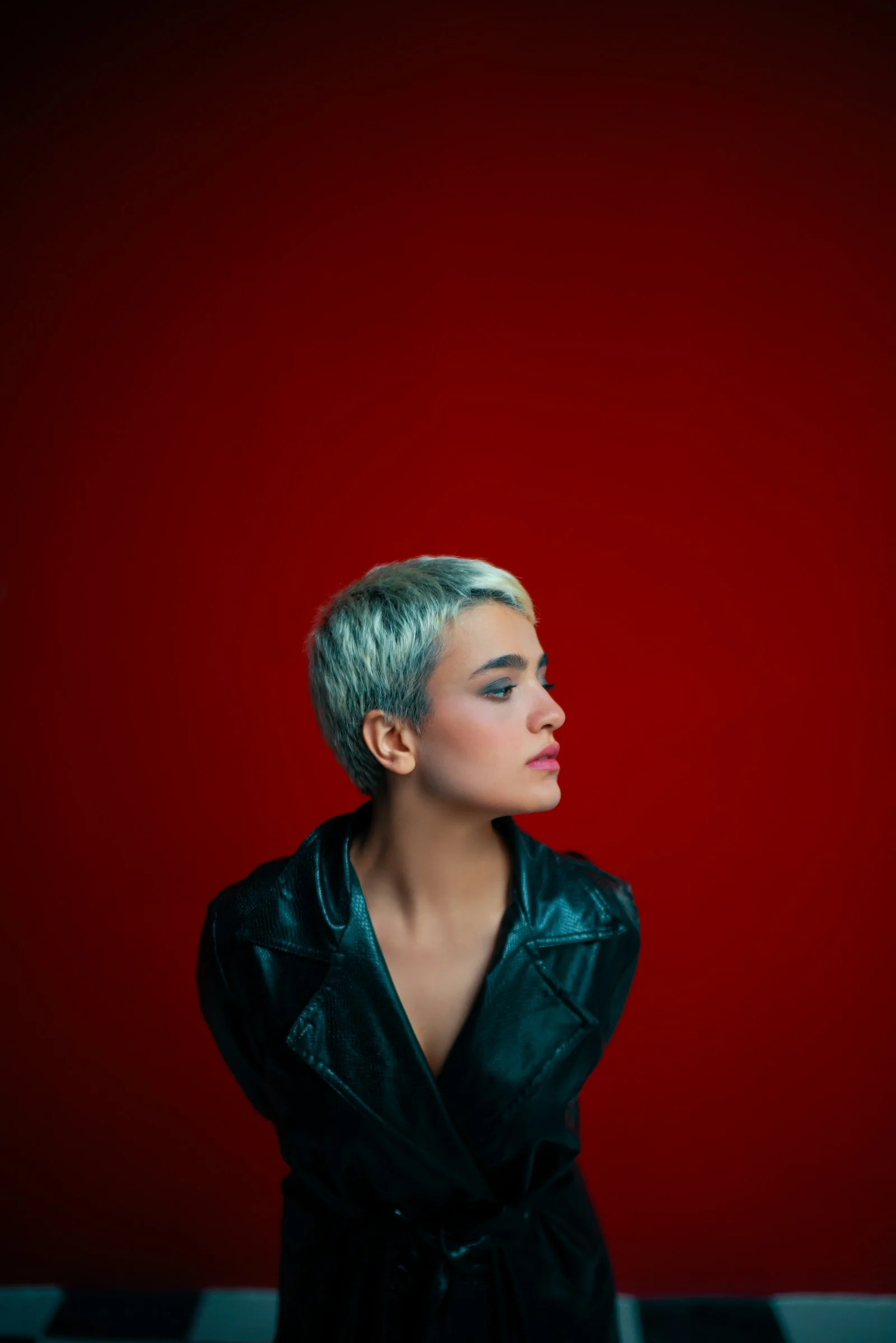 A woman in a black leather jacket standing in front of a red wall