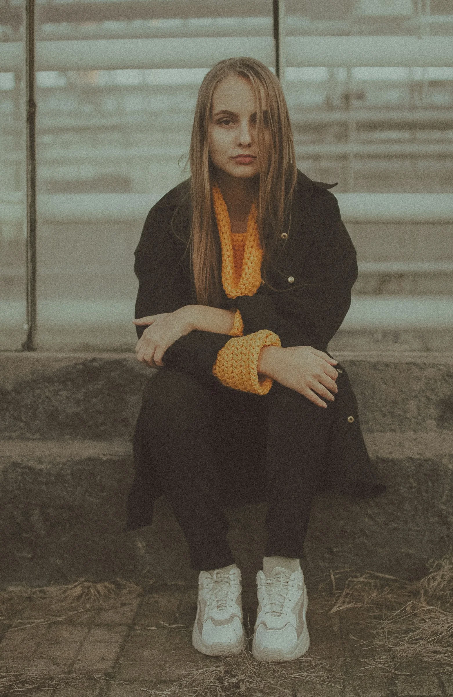 身穿黑色西装外套和黑色裤子的女子坐在水泥长凳上