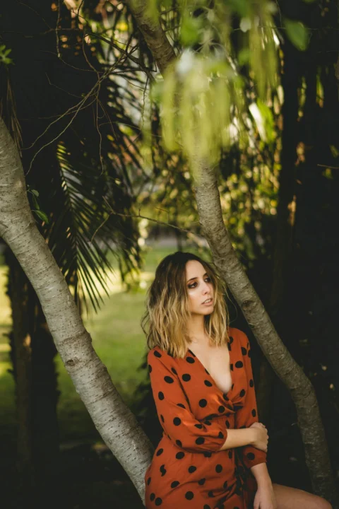 woman in red and black polka dot dress standing beside tree