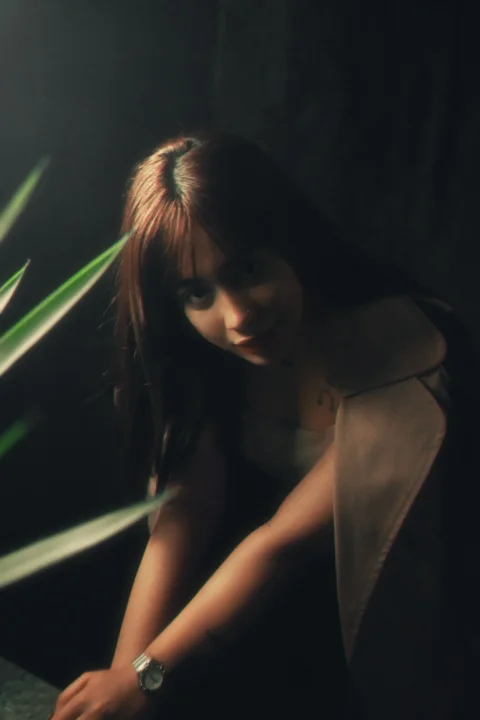 A woman leaning on a table next to a plant
