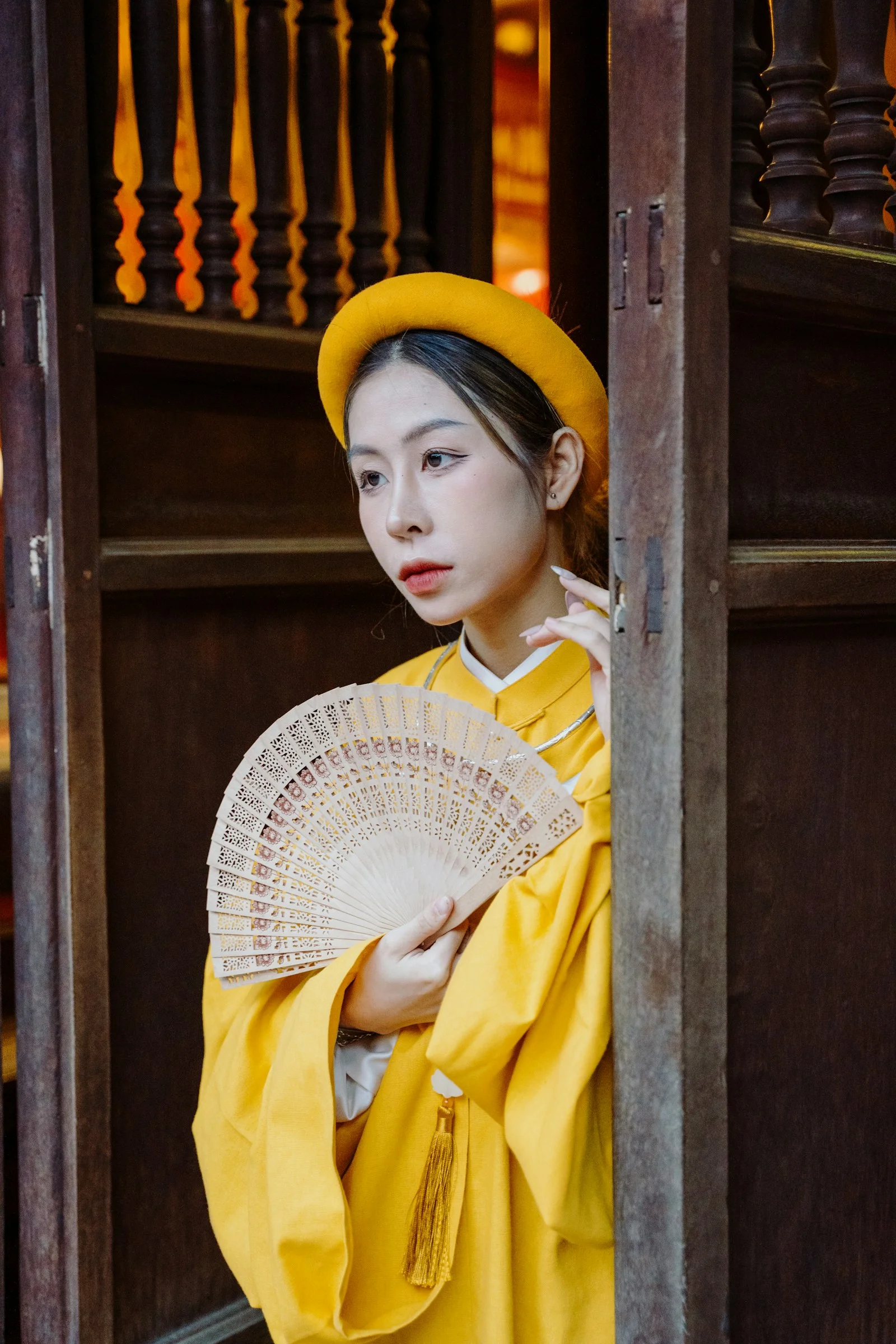 一位穿黄色服装、手持扇子的女性