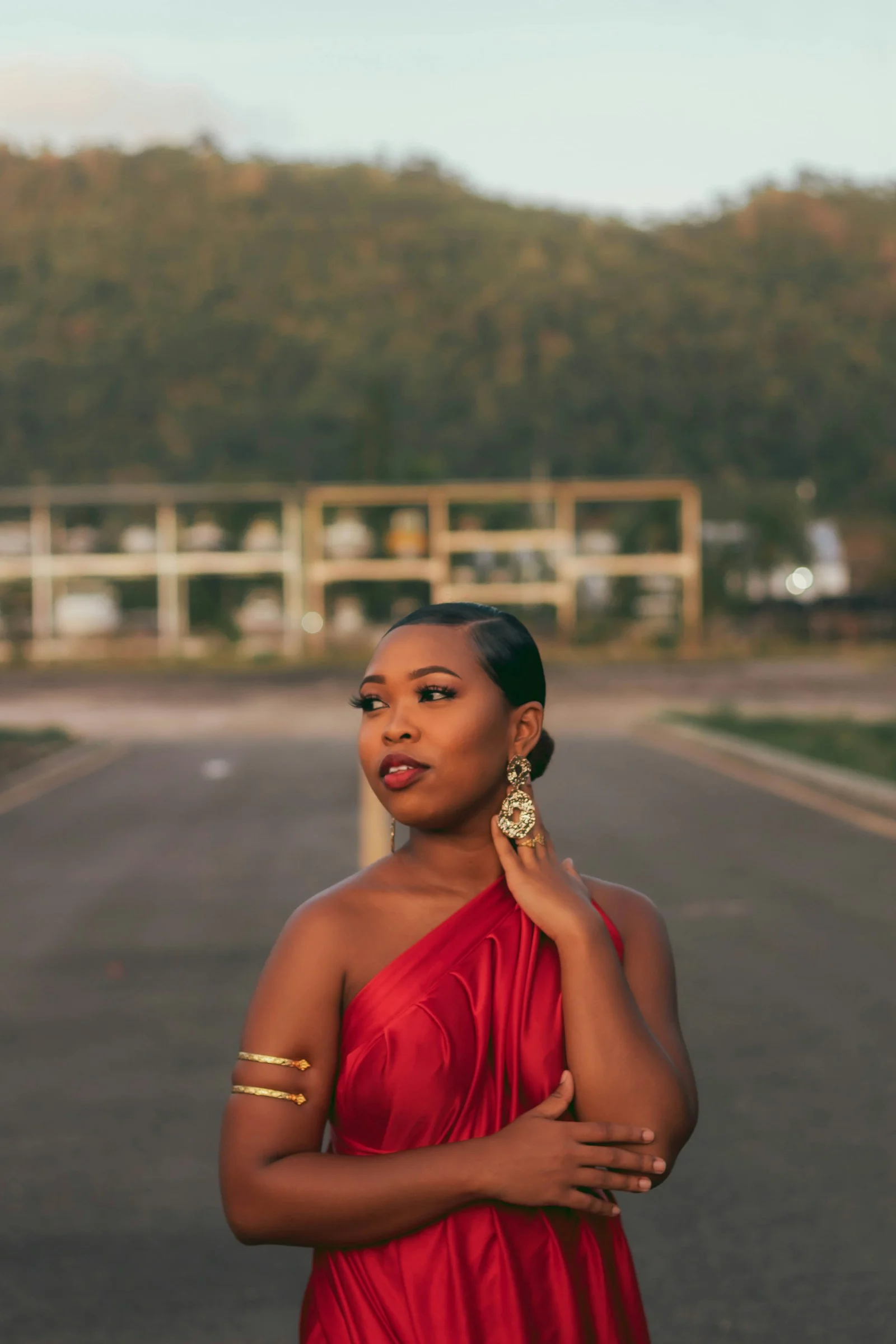 a woman in a red dress standing on the side of a road