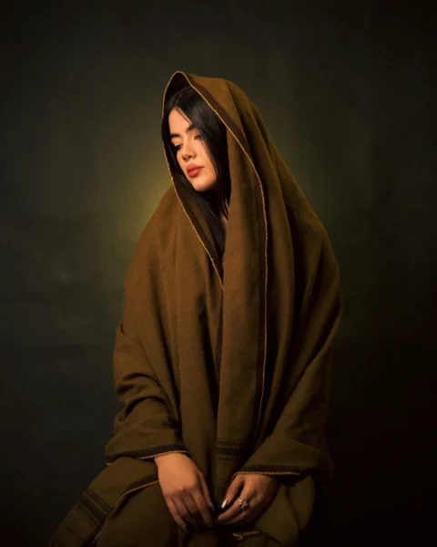 A woman in a brown robe sitting on a stool