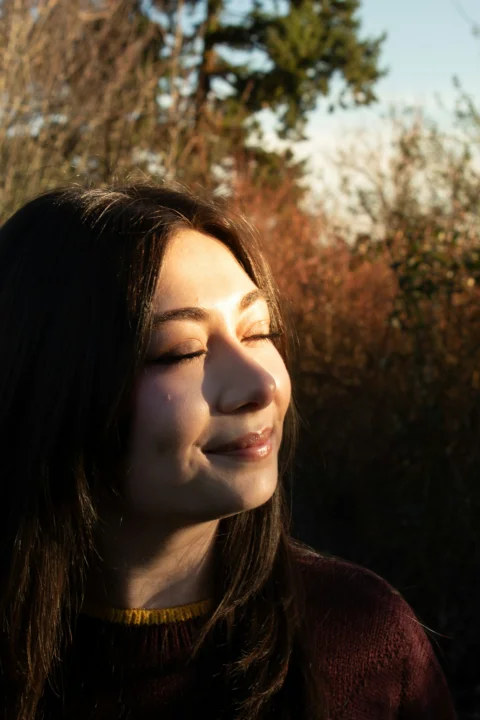 陽射しの中で目を閉じた若い女性
