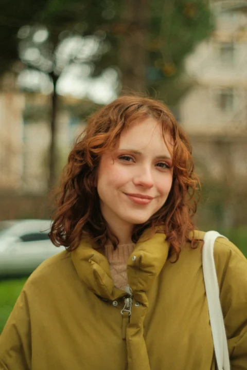 A woman with red hair is standing in the grass