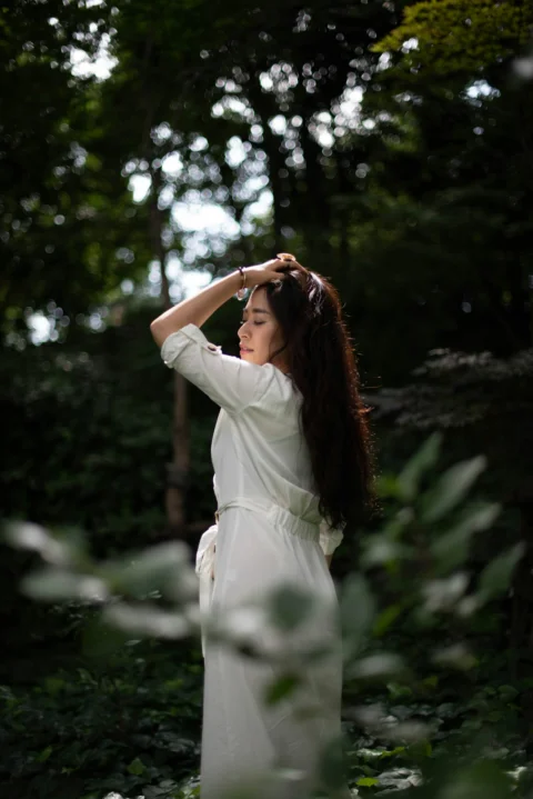 a woman in a white dress standing in a forest