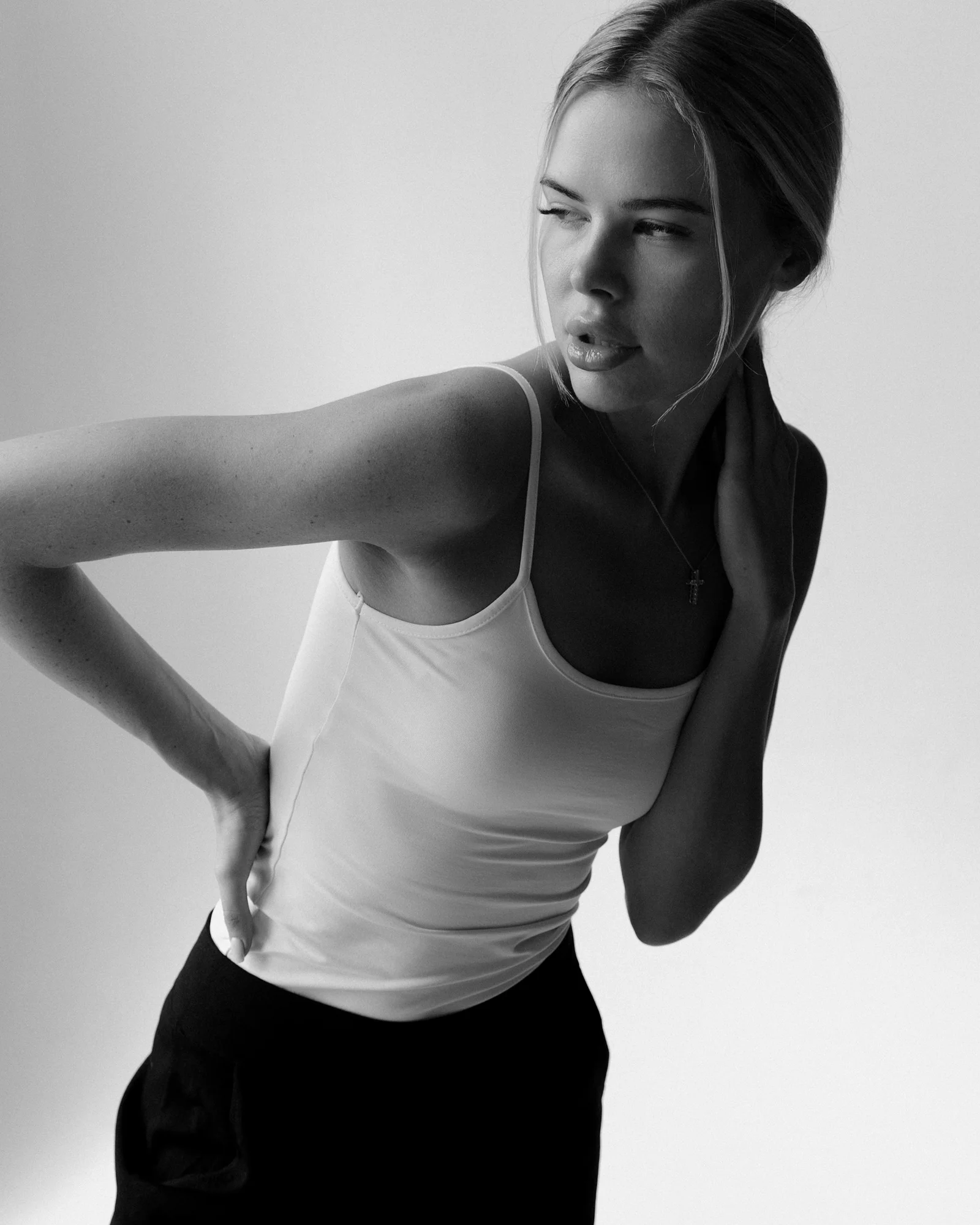 a woman in a tank top is holding her hand on her hip