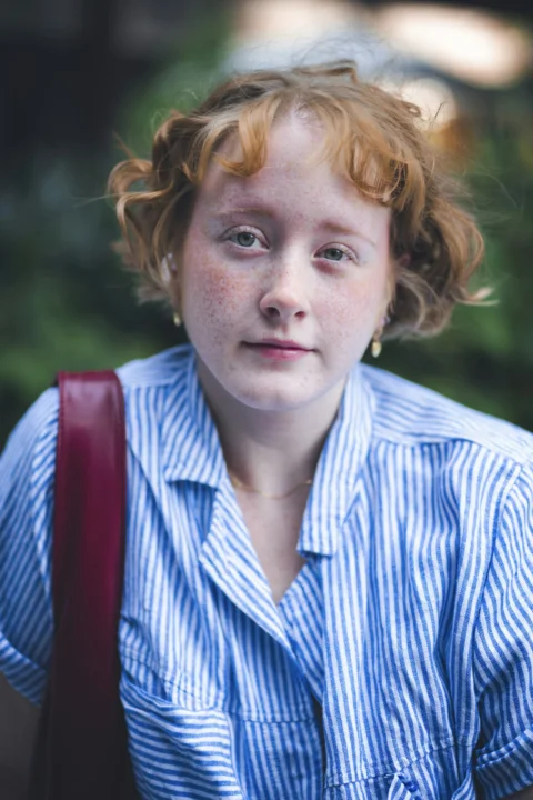 A young girl with red hair wearing a blue shirt