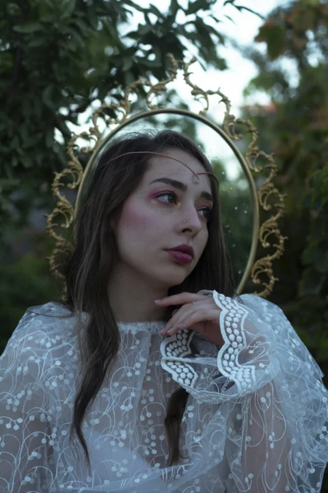 a woman in a white dress with a mirror behind her