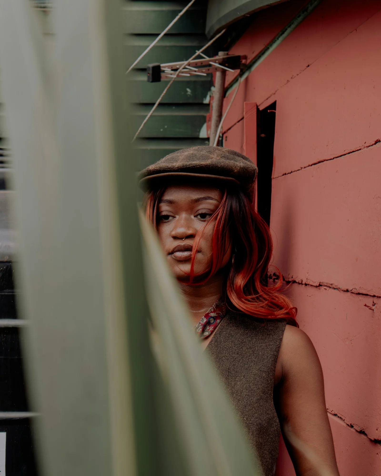 Woman poses by a pink wall and foliage