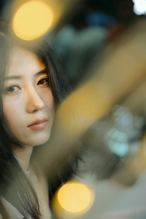Young woman's face framed by soft, warm bokeh lights