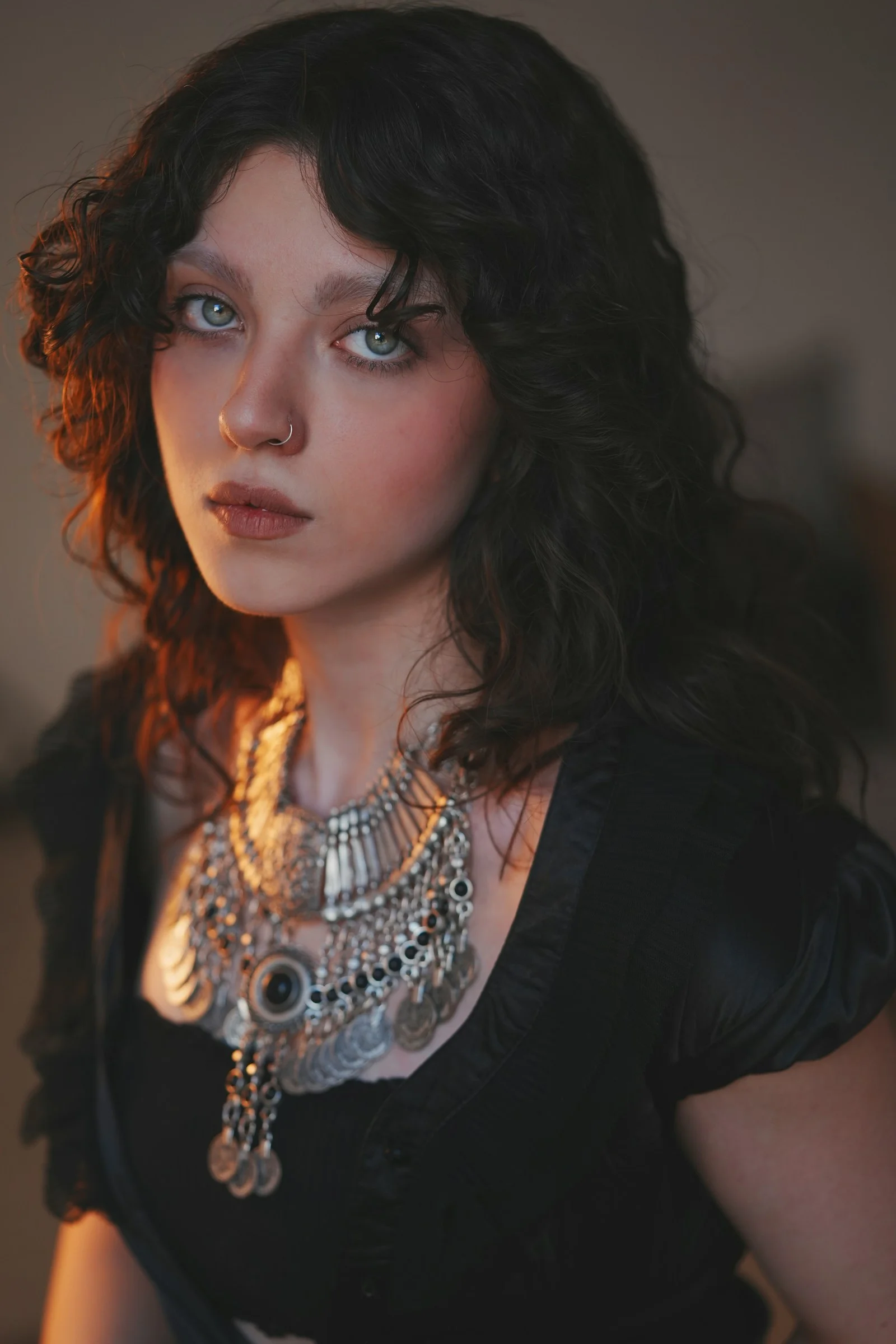 Young woman with dark curly hair and striking necklace