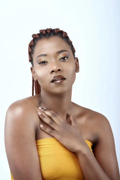 a woman in a yellow top with her hands on her chest
